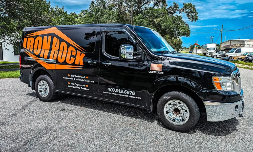 Black Nissan NV van with an orange partial wrap and lettering Black Nissan NV van with an orange partial wrap and lettering