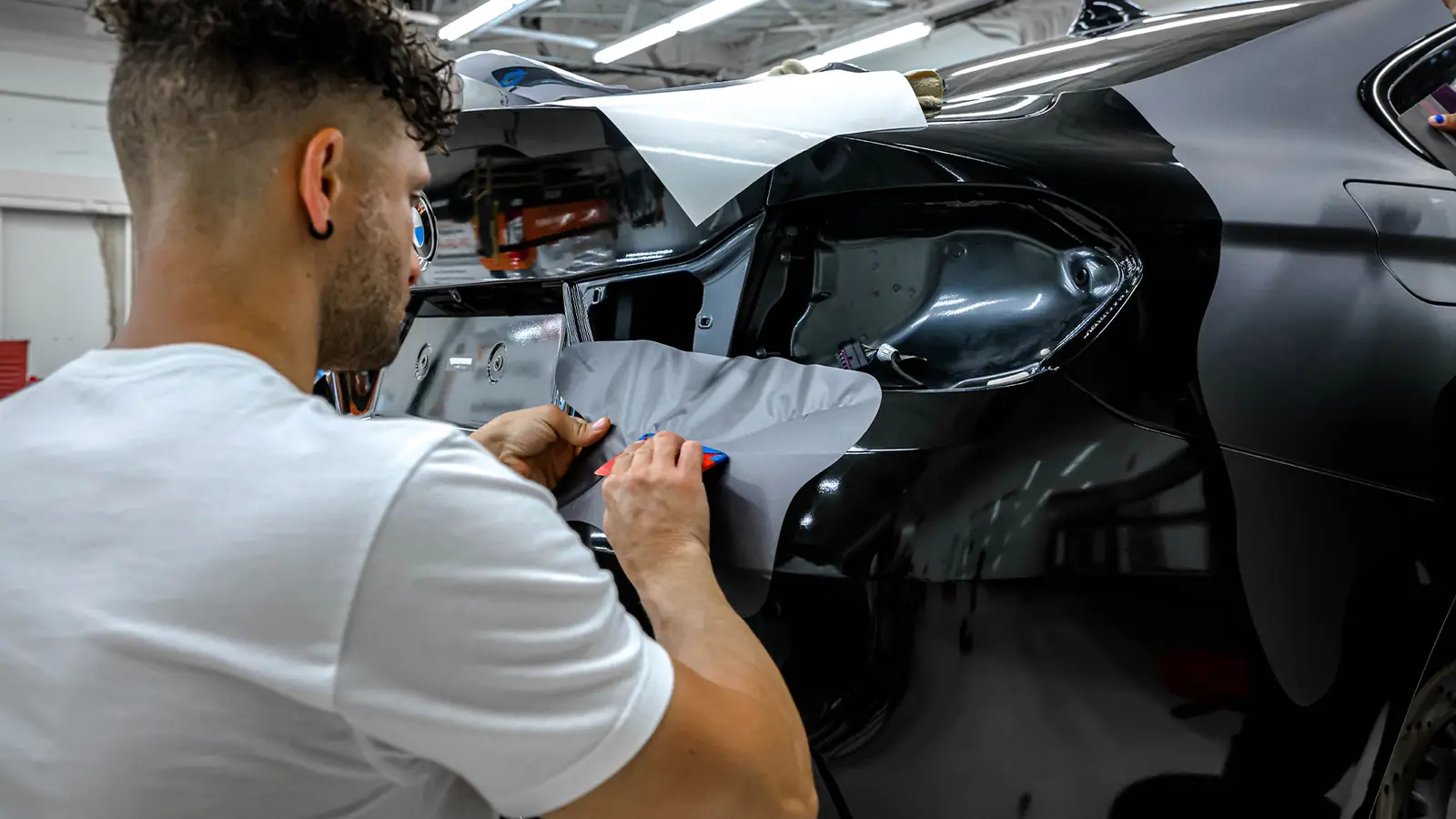 Installer applying vinyl wrap to a BMW M4 body panel