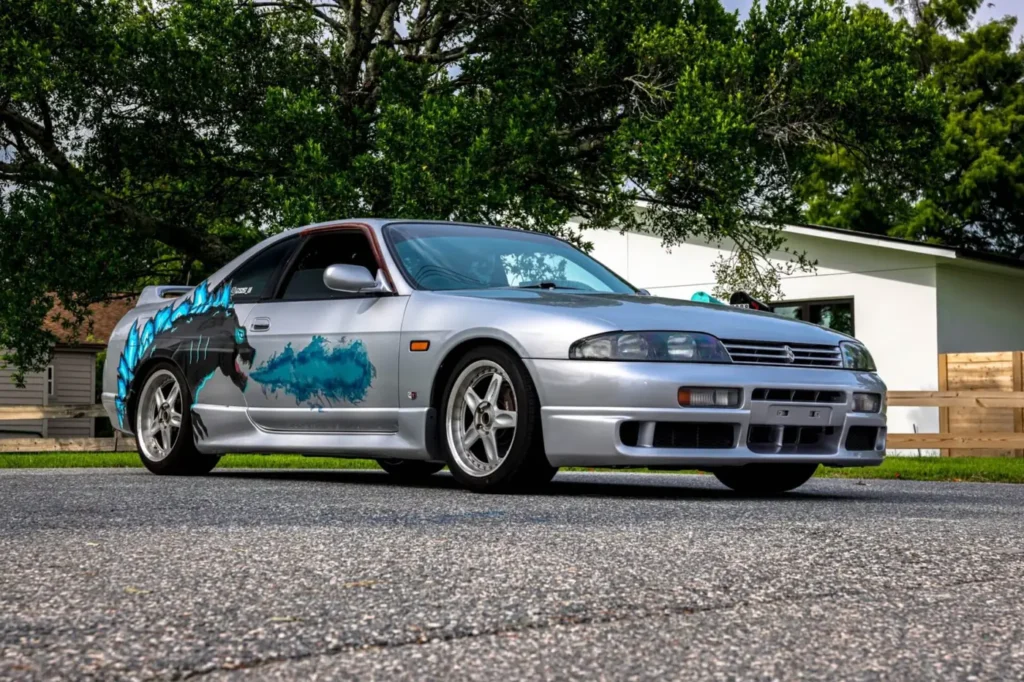 Silver Nissan Skyline with a Godzilla graphic wrap, front angle